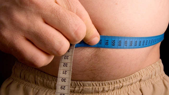 Ein Mann hält sich ein Zentimetermaß an seinen Bauch | Bildquelle: dpa/Alfred Schauhuber Ein Mann hält sich ein Zentimetermaß an seinen Bauch
