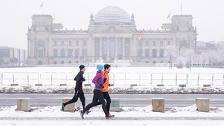 Drei Jogger vor dem Berliner Reichstagsgebäude