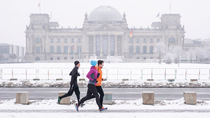 Drei Jogger vor dem Berliner Reichstagsgebäude