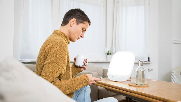 Eine Frau vor einer Tageslichtlampe | Bildquelle: picture alliance / dpa-tmn Eine Frau vor einer Tageslichtlampe