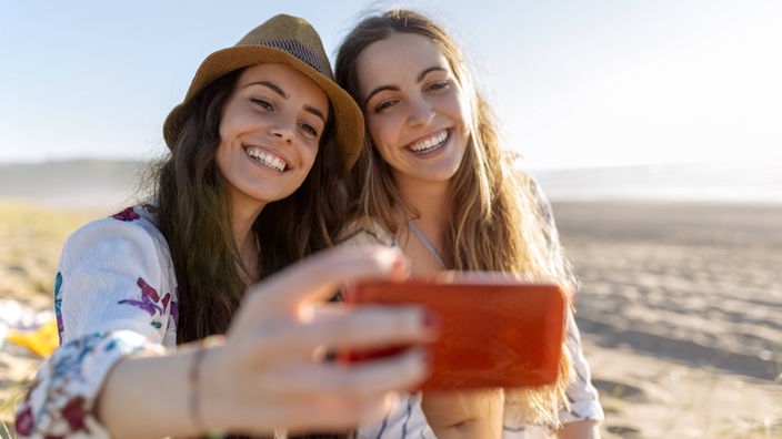 Zwei jugendliche Mädchen machen ein Selfie am Strand