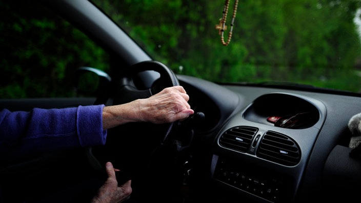 Eine Person dreht am Lenkrad in einem Auto.