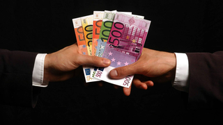 Symbolfoto: Eine Hand überreicht einer anderen Geldscheine
