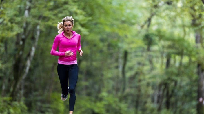 Frau joggt durch einen herbstlichen Wald
