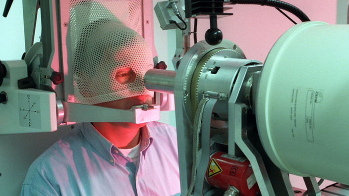 Im Berliner Hahn-Meitner-Institut ist ein Patient millimetergenau auf dem computergesteuerten Behandlungsstuhl mit Gesichtsmaske und Beißblock positioniert - zur Vorbereitung auf eine Augen-Tumor-Therapie mittels Protonenstrahl.