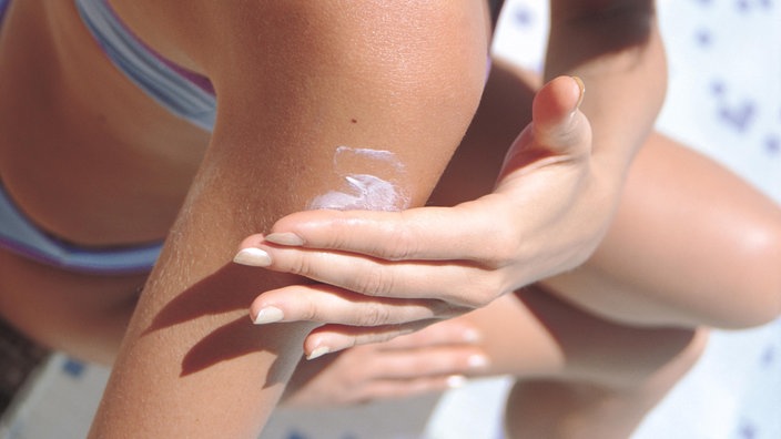 Eine Frau, deren Gesicht nicht zu sehen ist, cremt sich den Oberarm mit Sonnencreme ein. | Bildquelle: Mauritius Eine Frau, deren Gesicht nicht zu sehen ist, cremt sich den Oberarm mit Sonnencreme ein.