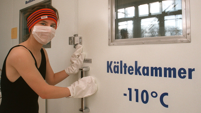 Mit Mundschutz, Stirnband und Handschuhen erprobt ein junges Mädchen die Kältekammer