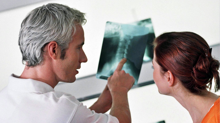 Arzt und Patientin schauen sich ein Röntgenbild an.
