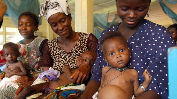 Drei schwarzafrikanische Mütter sitzen mit ihren kranken Kleinkindern im Krankenhaus von Kenema, Sierra Leone.
