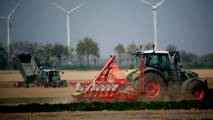Ein Bauer fährt mit seinem Traktor fährt über ein Feld.