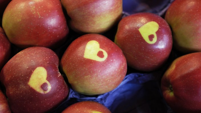 Das Foto zeigt zahlreiche Äpfel, die in der Mitte ihrer leuchtend roten Backen je ein grünes Herz haben.