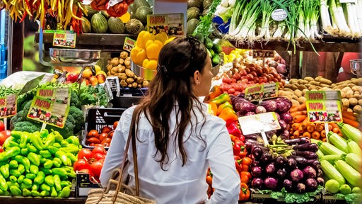 Eine Frau steht vor der Obst- und Gemüsetheke