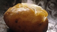 Eine dampfende, gekochte Kartoffel.