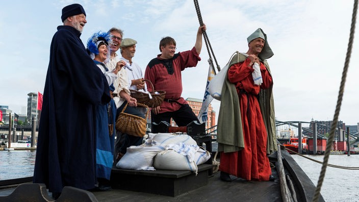Nachgestellte historische Szene: Sechs Menschen auf einem Boot mit Salzsäcken