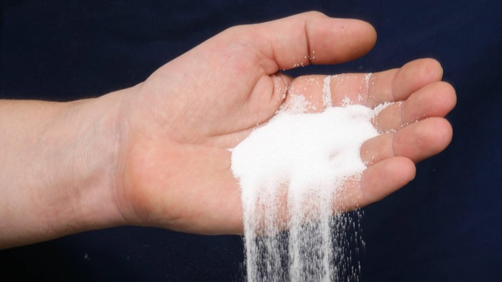 Eine Hand schüttet eine große Menge Salz in einem Kochtopf.