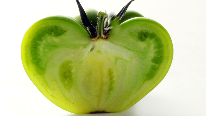 Eine halbe, grüne Tomate.
