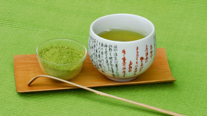 Eine Schale mit Grüntee-Pulver und eine Tasse mit aufgebrühtem Tee