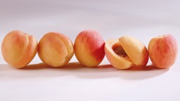 Frische Aprikosen nebeneinander, eine geöffnet