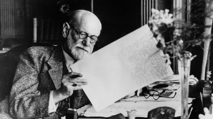Der Psychoanalytiker Sigmund Freud sitzt an seinem Schreibtisch un Hampstead und liest Zeitung.