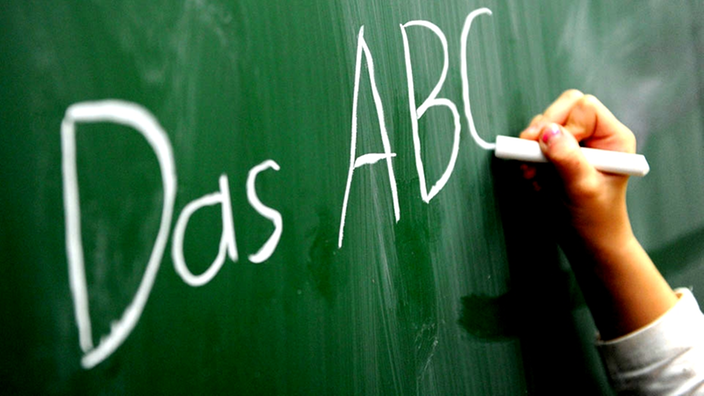 Ein Kind schreibt ABC an die Tafel.