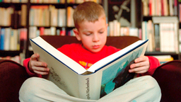 Ein Junge liest in einem großen Märchenbuch.