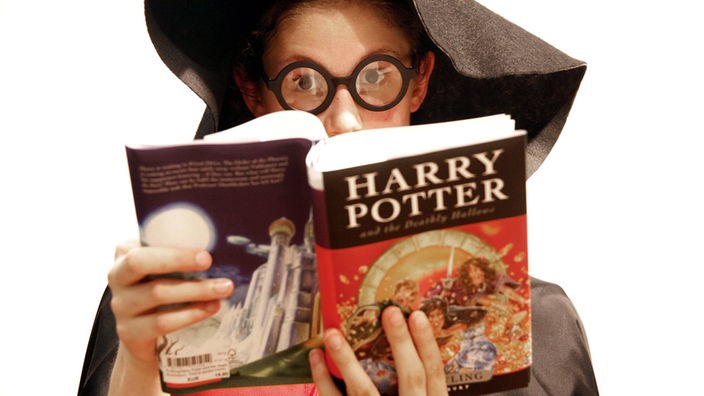 Ein Mädchen liest als Hexe verkleidet Harry Potter