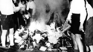 Bücherverbrennung im Dritten Reich: Eine Menschenmenge und ein brennender Scheiterhaufen aus Büchern.