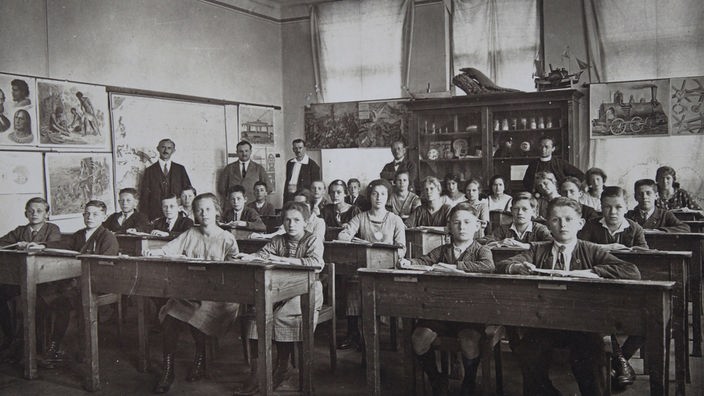Lehrer, Schüler und Schülerinnen um 1900 in einem Klassenzimmer
