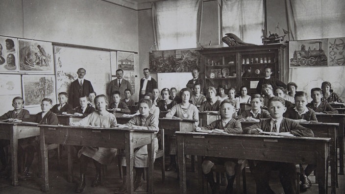 Lehrer, Schüler und Schülerinnen um 1900 in einem Klassenzimmer | Bildquelle: picture alliance / IMAGNO/Austri Lehrer, Schüler und Schülerinnen um 1900 in einem Klassenzimmer