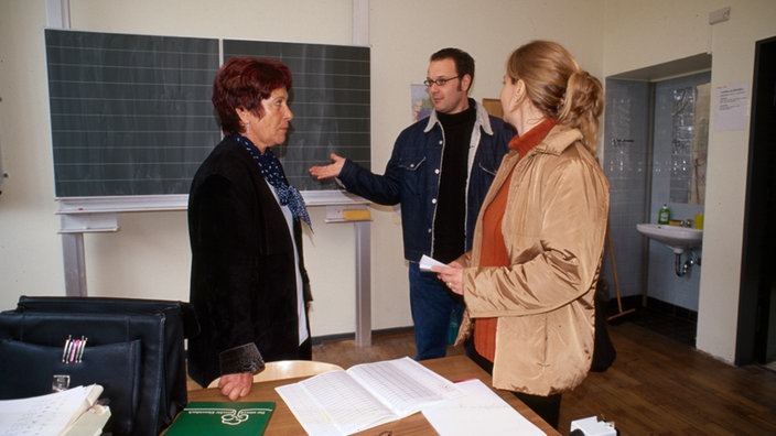 Zwei Eltern unterhalten sich im Klassenraum mit einer Lehrerin. | Bildquelle: WDR/Regina Bermes Zwei Eltern unterhalten sich im Klassenraum mit einer Lehrerin.