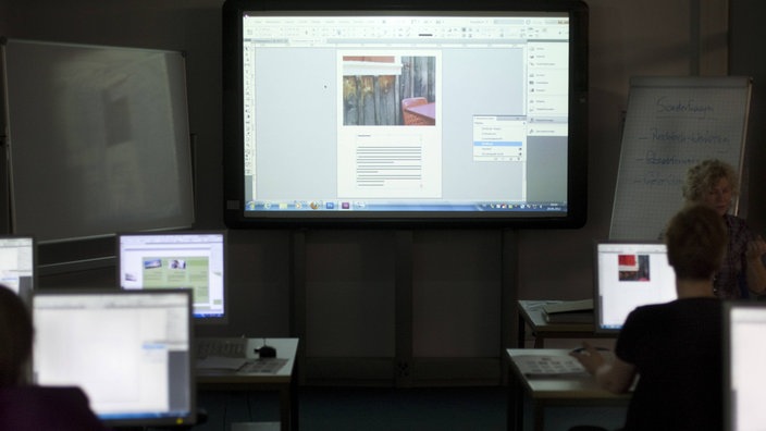 Computerbildschirme und ein Whiteboard in einem abgedunkelten Raum der VHS in Köln | Bildquelle: imago/photothek Computerbildschirme und ein Whiteboard in einem abgedunkelten Raum der VHS in Köln