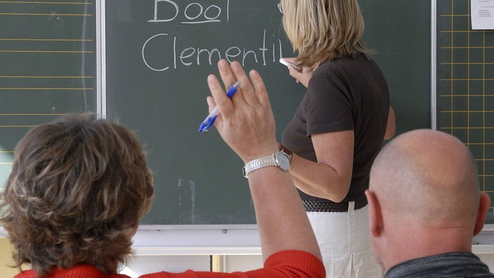 Zwei Erwachsene bei einem Alphabetisierungskurs vor einer Tafel | Bildquelle: Imago stock Zwei Erwachsene bei einem Alphabetisierungskurs vor einer Tafel