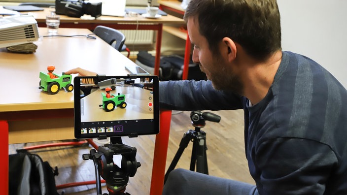 Ein VHS-Mitarbeiter platziert ein Playmobilfahrzeug für einen Stop-Motion-Trick | Bildquelle: VHS Leipzig / Caroline Baetge Ein VHS-Mitarbeiter platziert ein Playmobilfahrzeug für einen Stop-Motion-Trick