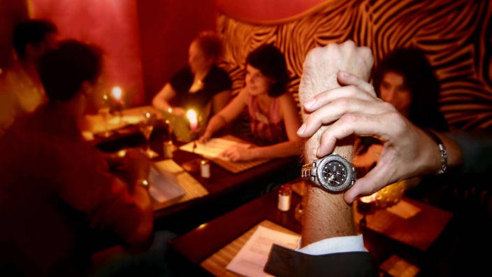 Mann schaut beim Speeddating auf seine Armbanduhr