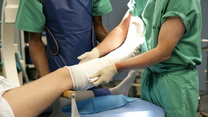Im Krankenhaus wird nach einer Operation ein Unterschenkel eingegipst | Bildquelle: WDR / mauritius images (imageBROKER / Jochen Tack) Im Krankenhaus wird nach einer Operation ein Unterschenkel eingegipst