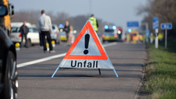 Ein Warndreieck mit der Aufschrift "Unfall" steht auf einer Autobahn.