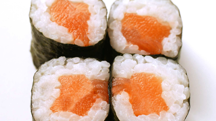 Vier Rollen Sushi aus Reis und Lachs.