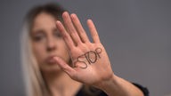 Überforderung bei der Pflege zu Hause: Junge Frau zeigt "Stop"