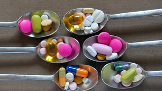 Verschiedene Tabletten und Kapseln auf Silberlöffeln.