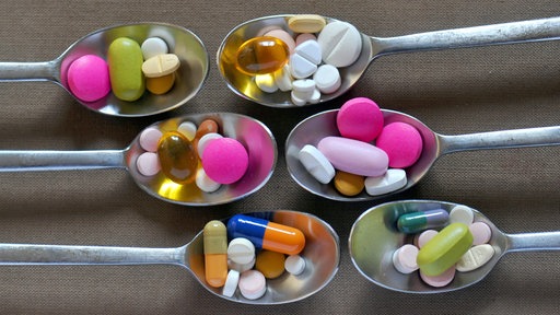 Verschiedene Tabletten und Kapseln auf Silberlöffeln.