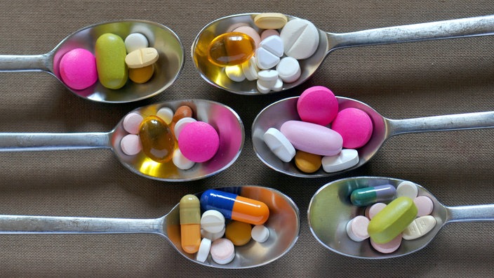 Verschiedene Tabletten und Kapseln auf Silberlöffeln.