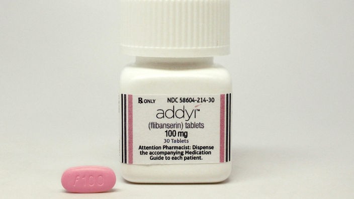 Eine pinkfarbene Pille liegt neben einer Dose mit der Aufschrift "addyi".