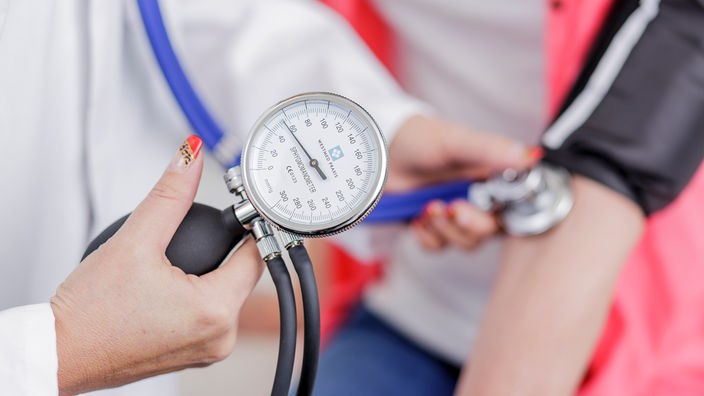 Eine Ärztin misst den Blutdruck eines Patienten.