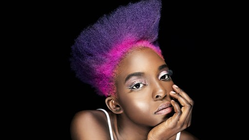 Eine junge schwarze Frau mit lila und pink gefärbten Haaren