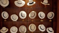 Das Bild zeigt viele Panamahüte - Herrenhüte aus besonderen Palmenblättern - auf Ständern in einem Schaufenster.