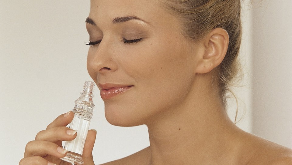 Eine Frau riecht an einer Parfumflasche.