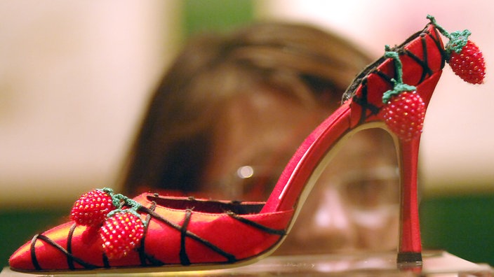 Roter Damenschuh von Manolo Blahnik mit sehr hohem Absatz und Bommeln aus Himbeeren. | Bildquelle: dpa Roter Damenschuh von Manolo Blahnik mit sehr hohem Absatz und Bommeln aus Himbeeren.