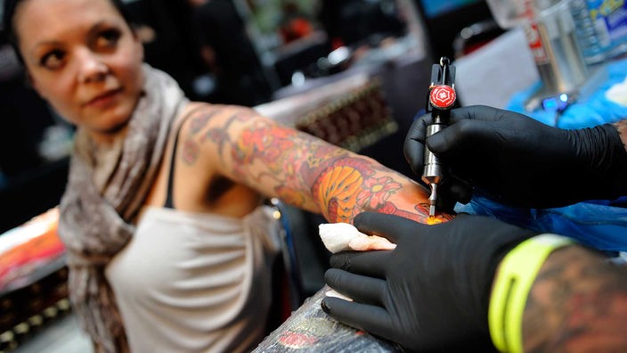 Eine Frau bekommt ein Tattoo am Arm gestochen.