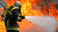 Feuerwehrmann hält Wasserschlauch in Flammen