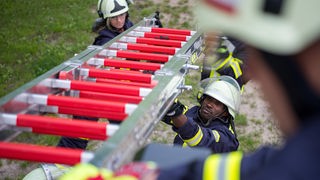 Feuerwehrübung der Freiwilligen Feuerwehr Flechtorf in Lehre-Flechtorf (Niedersachsen) eine Leiter mit anderen Feuerwehrmännern und -frauen entgegen.